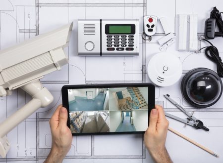 A Person Watching Footage On Digital Tablet With Security Equipment On Blueprint