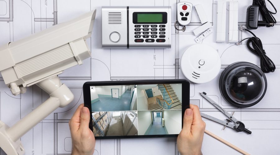 A Person Watching Footage On Digital Tablet With Security Equipment On Blueprint