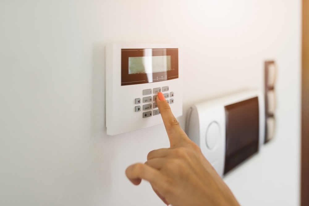 Young woman entering authorization code pin on home alarm keypad