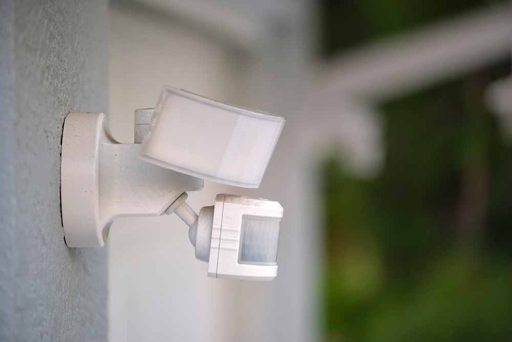 Motion sensor with light detector mounted on exterior wall of private house as part of security system