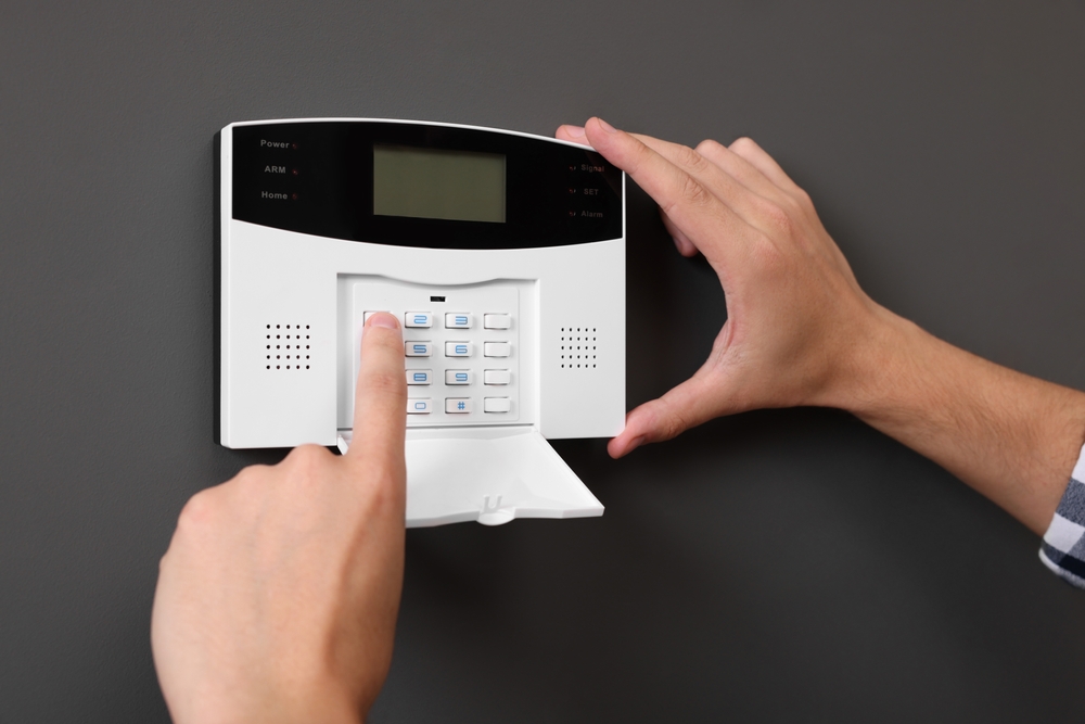 Man entering code on home security alarm system