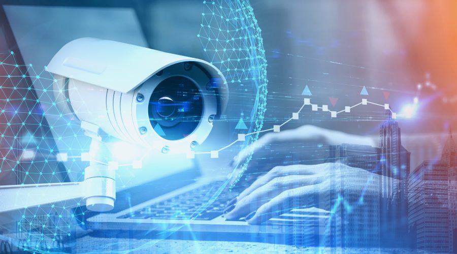 Hands of woman typing on laptop with double exposure of CCTV camera