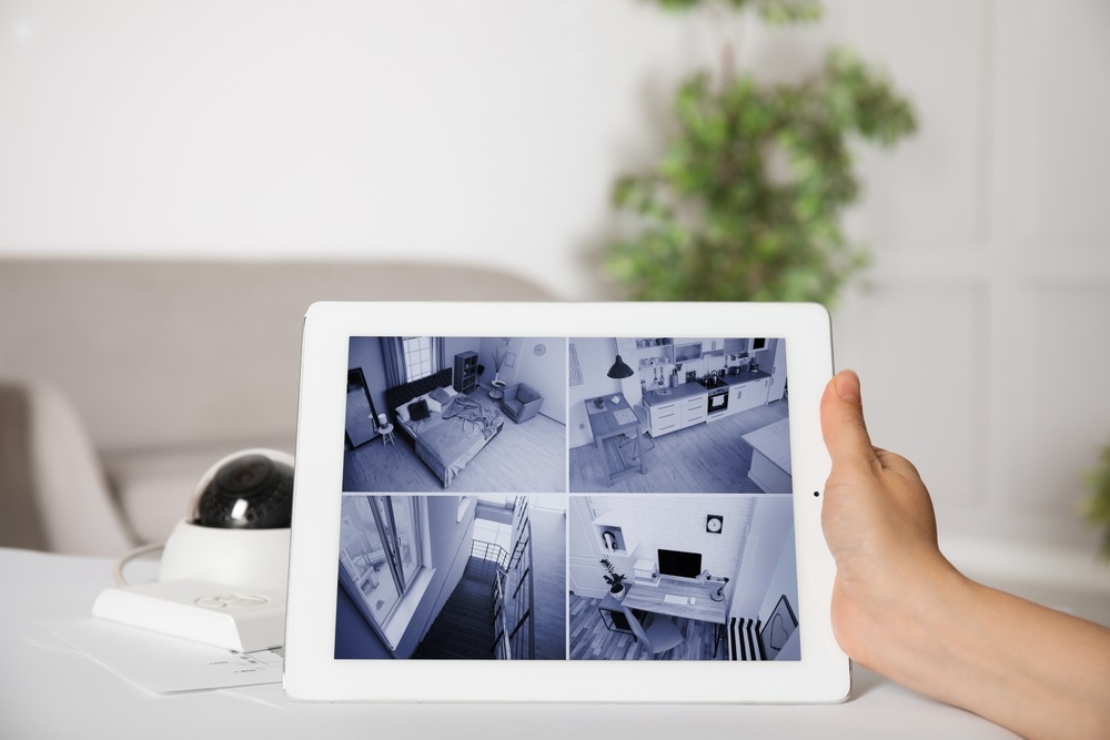 Woman monitoring CCTV camera on tablet at table indoors