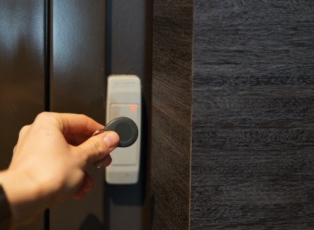 holding a keychain with a key fob near a key reader access device on a wall