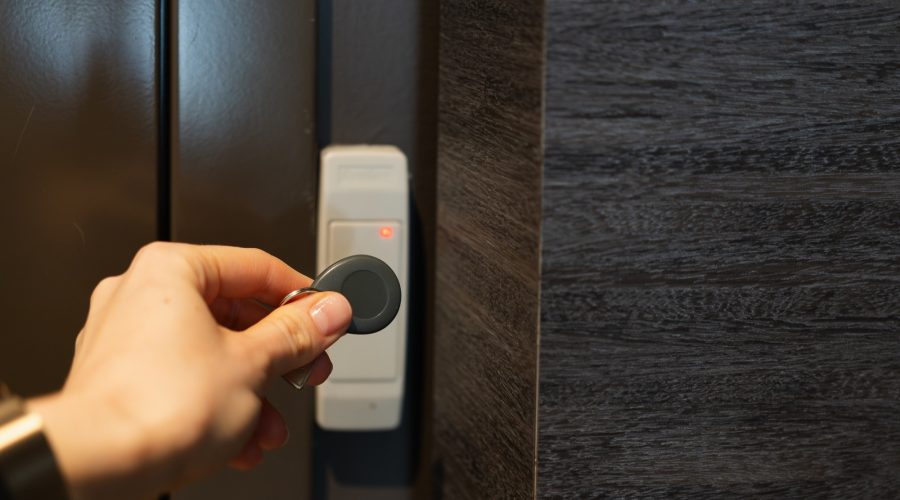 holding a keychain with a key fob near a key reader access device on a wall