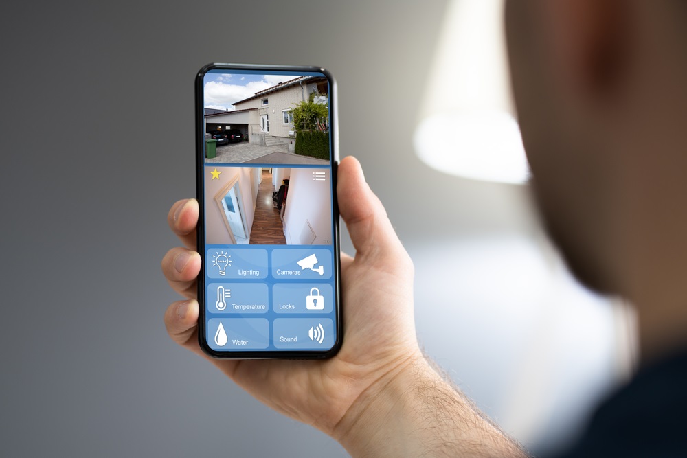 Man monitoring modern cctv cameras on smartphone indoors