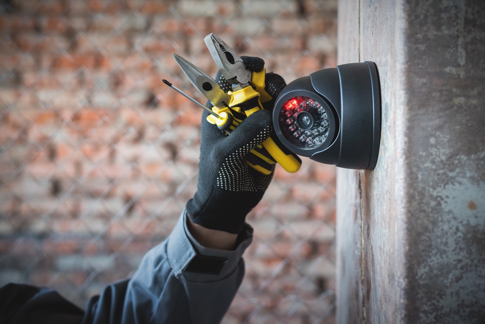 Security camera on the wall close up and worker hand