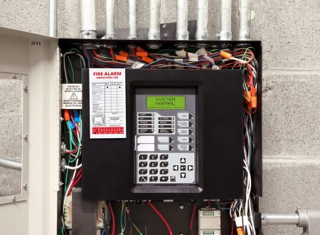 Fire alarm control panel in service room with fire inspection tag. Open cabinet of single-stage fire alarm system in strata