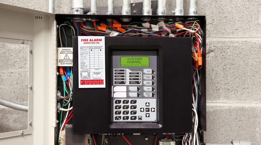 Fire alarm control panel in service room with fire inspection tag. Open cabinet of single-stage fire alarm system in strata