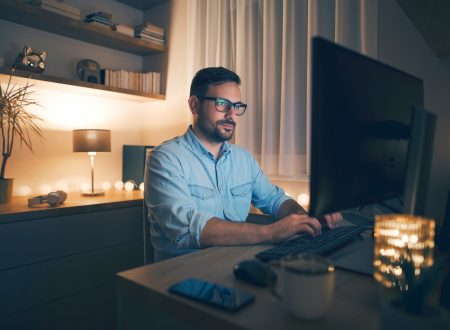 Modern young man working remotely from home at night.